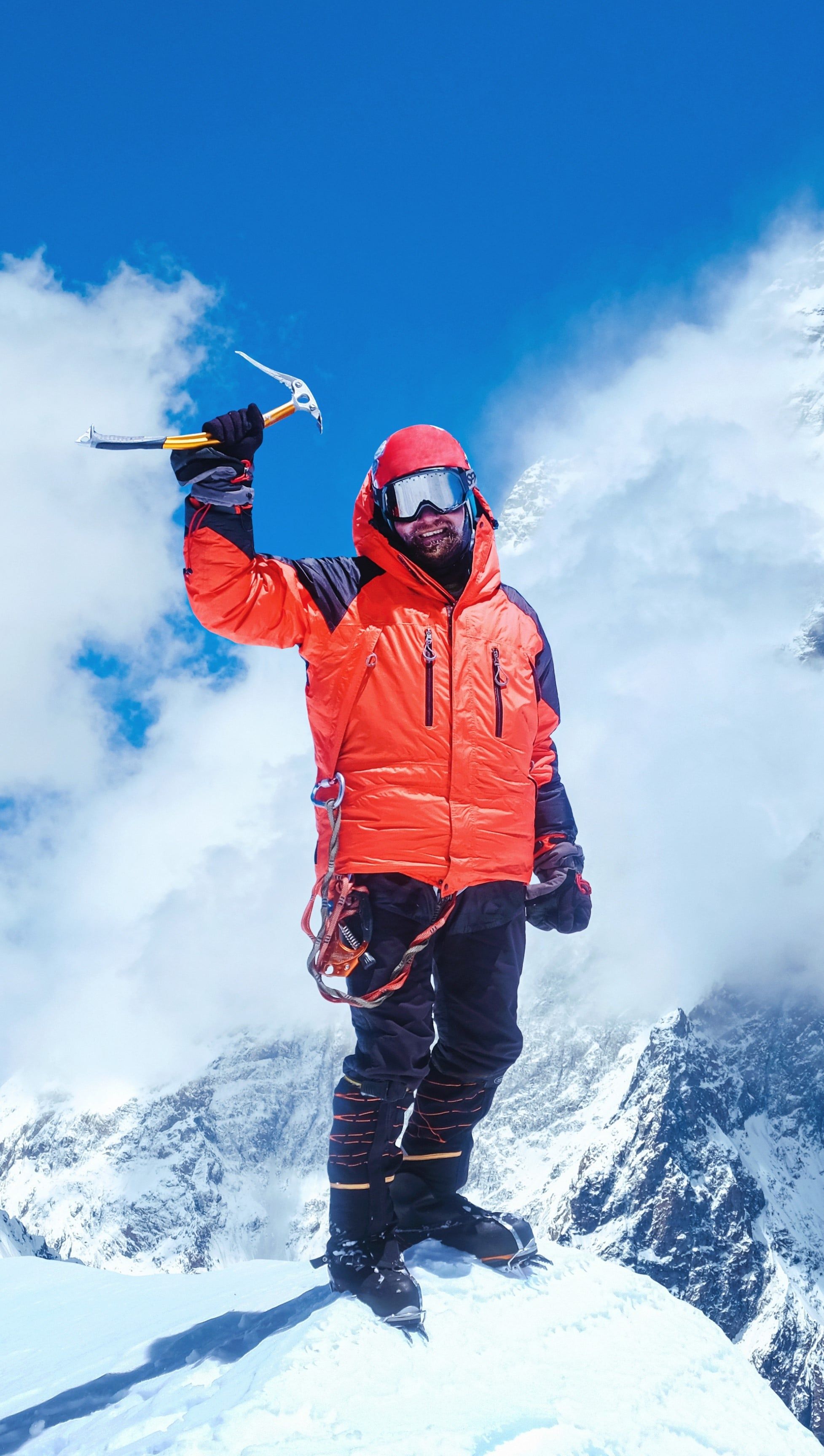 A climber in a red jacket on a snowy summit