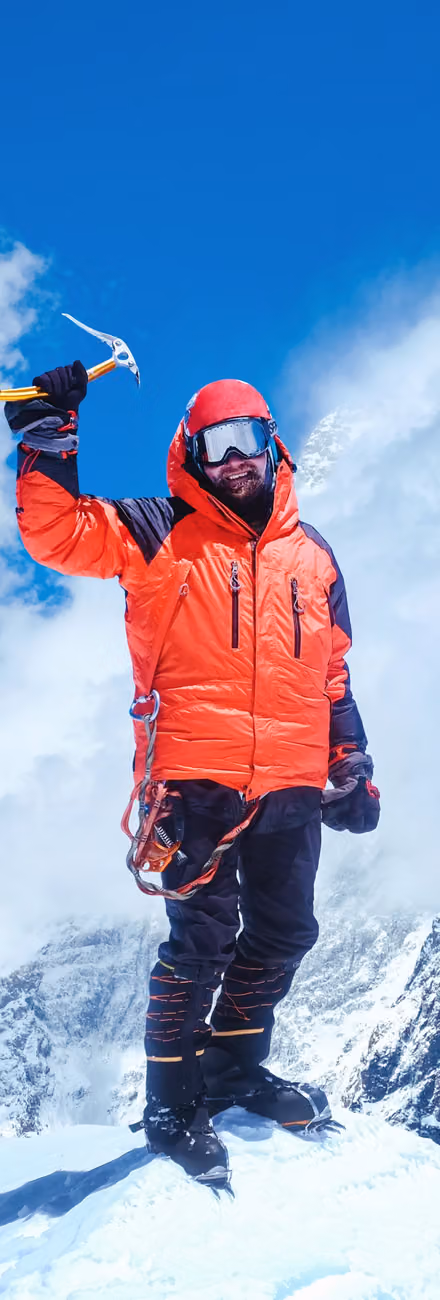 A climber in a red jacket on a snowy summit